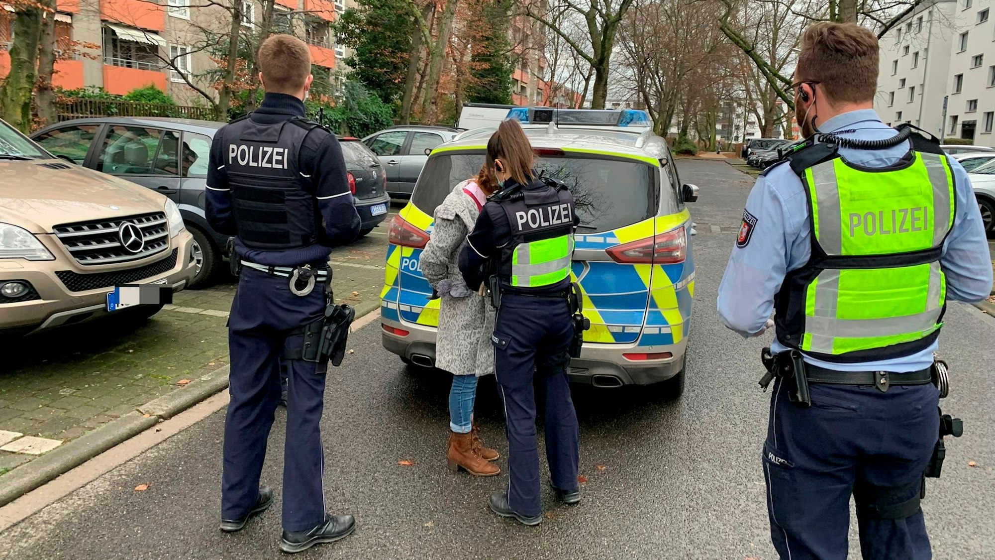 Eine Polizistin nimmt eine Frau fest, zwei Polizisten stehen daneben.