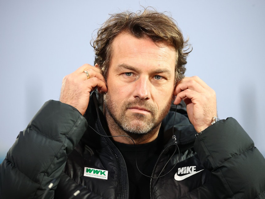 Augsburg-Trainer Markus Weinzierl steckt sich vor der wichtigen Partie gegen Fürth Kopfhörer in seine Ohren.