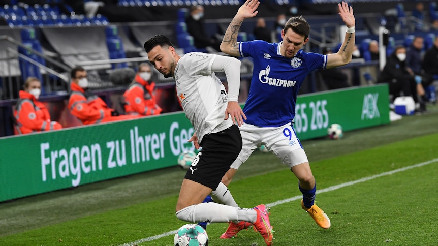 Gladbach-Profi Ramy Bensebaini (l.) im Duell mit Schalkes Benito Raman (r.) bei der Bundesliga-Partie am 20. März 2021 in der Gelsenkirchener Arena.