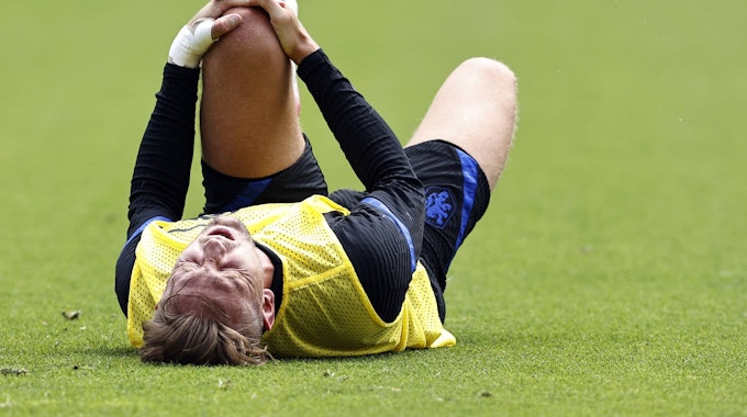 Der niederländische Nationalspieler Luuk de Jong liegt auf dem Rücken und hält mit beiden Händen das linke Knie.