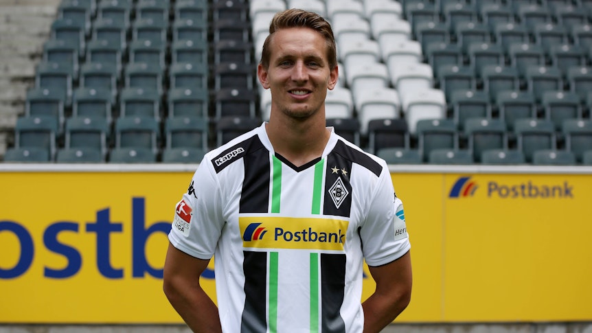 Luuk de Jong steht auf dem Rasen im Borussia-Park. Er hat die Hände hinter dem Rücken verschränkt, dabei lächelt er in die Kamera des Fotografen.