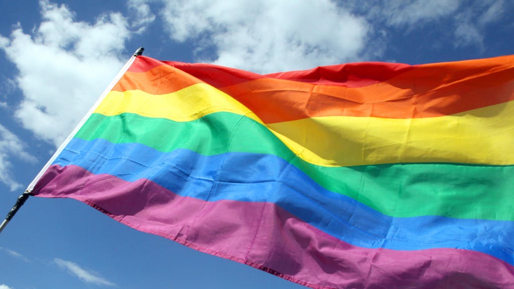 Die wehende Regenbogenflagge der LGBTQI+-Communitys wird auch Pride-Flagge genannt.