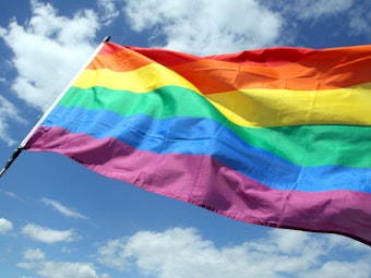 Die wehende Regenbogenflagge der LGBTQI+-Communitys wird auch Pride-Flagge genannt.