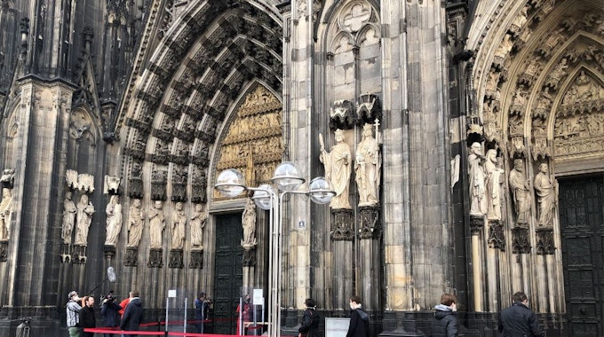 Besucher warten am Eingang des Kölner Doms.