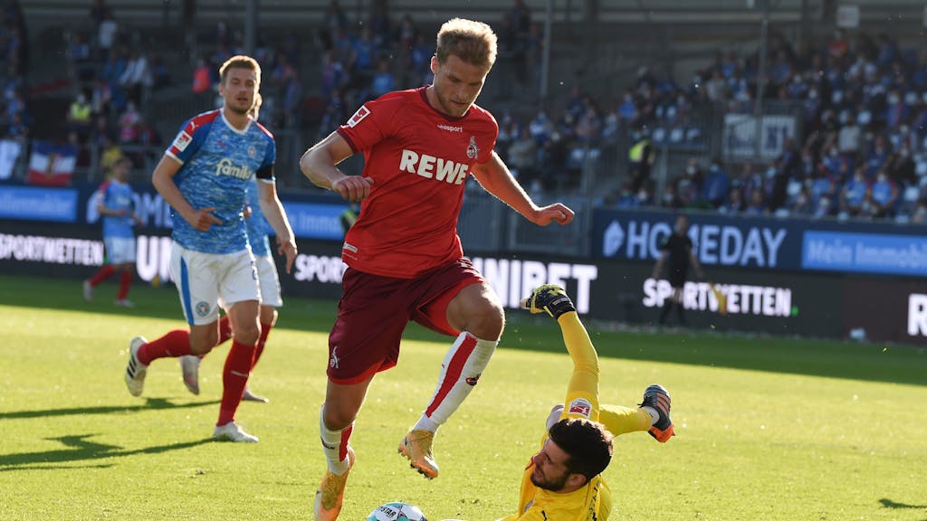 Sebastian Andersson (1. FC Köln) springt über Kiel-Keeper Ioannis Gelios.
