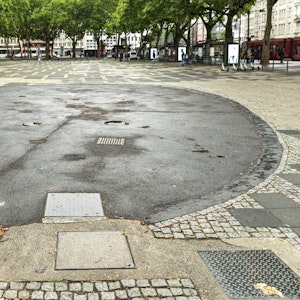 Ein Brunnen auf dem Neumarkt in Köln ist mit Bitumen verfüllt worden, so dass von ihm nur noch eine runde Fläche übrig ist.