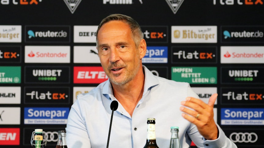 Trainer Adi Hütter blickt in den Presseraum des Borussia-Parks, während er spricht gestikuliert er mit seiner linken Hand.