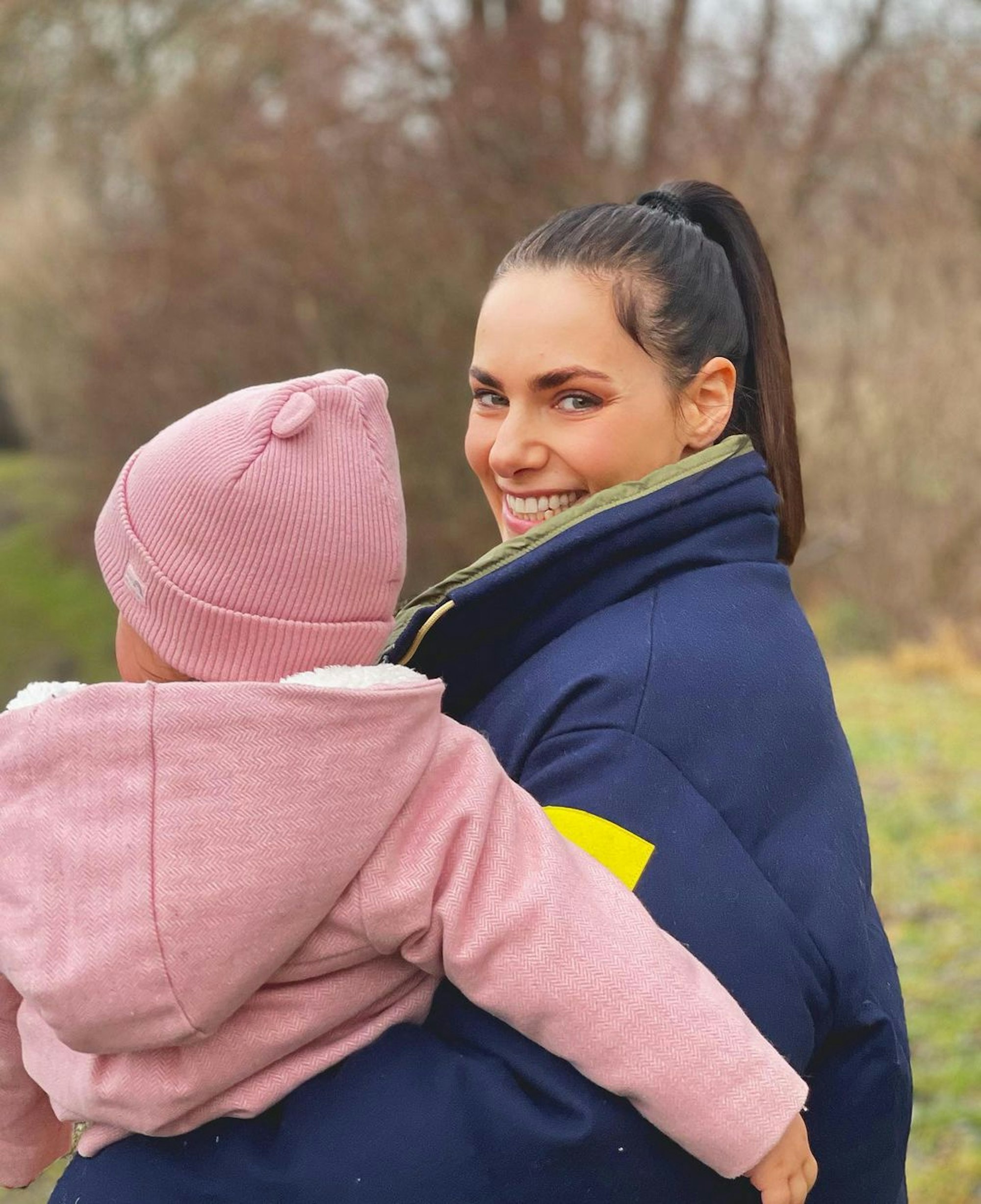Esther Sedlaczek trägt ihre Tochter auf dem Arm.
