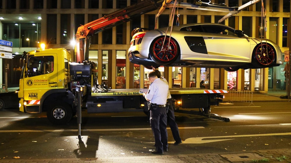 Unter den Augen der Kölner Polizei wird ein Sportwagen auf den Abschlepper geladen.