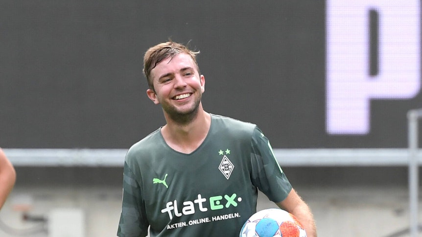 Gladbachs Christoph Kramer hält mit lachendem Gesicht einen Fußball unterm Arm.