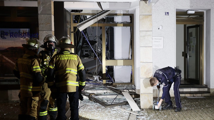 Feuerwehrleute stehen vor dem Selbstbedienungscenter der Deutschen Bank in Osterrath, in dem unbekannte Täter am 28. Dezember 2021 einen Geldautomaten gesprengt hatten.