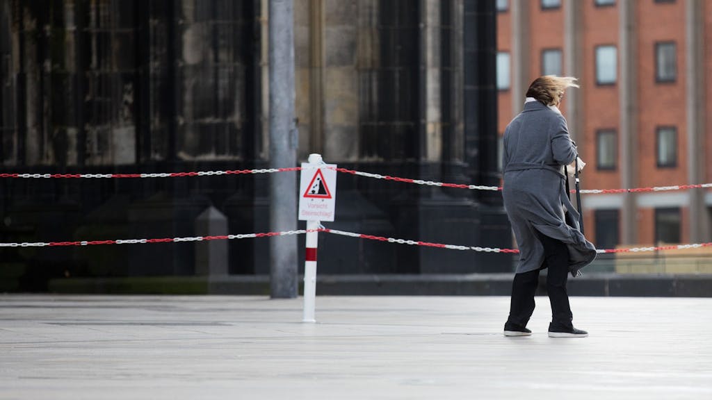 Eine Frau kämpft am 18.01.2018 auf der zum Teil gesperrten Domplatte in Köln (Nordrhein-Westfalen) mit einer Windböe.&nbsp;