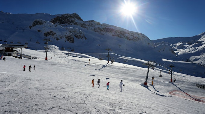 Mehrere Skifahrer fahren eine schneebedeckte Piste herab.