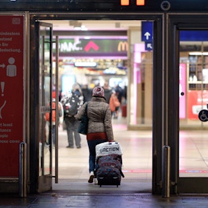 Köln: Eine Reisende geht mit einem Rollkoffer in den Hauptbahnhof.