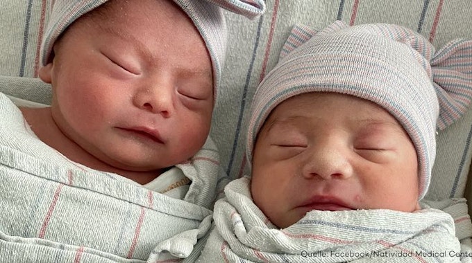 Neugeborene Zwillinge liegen nebeneinander im Kinderbett und schlafen.