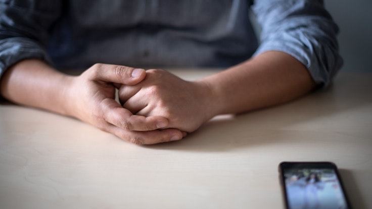 Ein Smartphone liegt in unserem Symbolbild vor einem jungen Mann auf dem Tisch. Weltweit verbreitet sich die Omikron-Variante immer weiter. Ein eher seltenes Symptom kennen die wenigsten: es betrifft die Finger und Zehen.