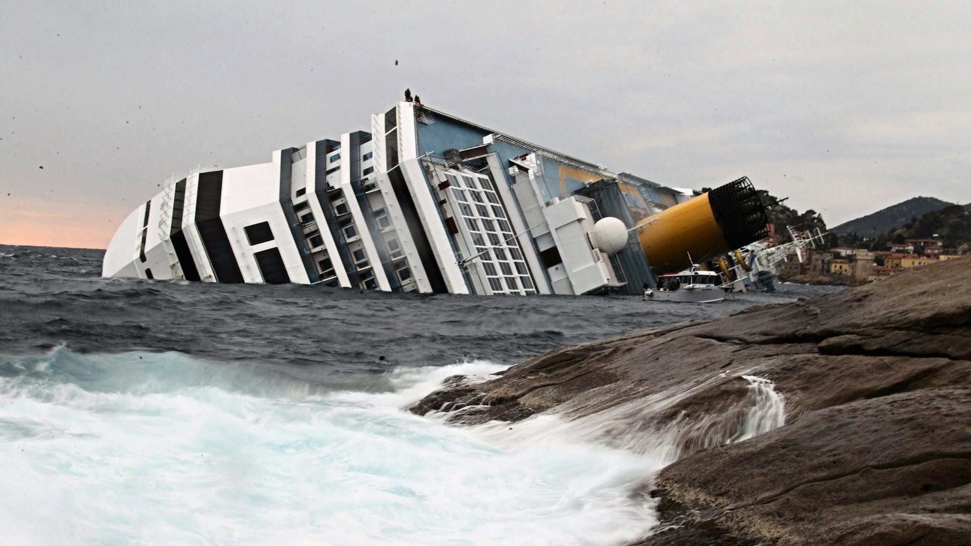 A file picture dated 16 January 2012 shows waves crashing against the rocks as the Costa Concordia Cruise ship lists off the coast of the island of Giglio, Itlay. On 15 October 2012 experts are due to present their findings at a pre-trial hearing dealing with the case of the capsized Italian cruise ship Costa Concordia, in Grosseto, Italy.