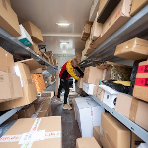 Ein DHL-Mitarbeiter sortiert in seinem Transporter die Pakete und Päckchen für die nächsten Zustellungen. (Zu dpa "Zusteller tragen vor Weihnachten Millionen Päckchen aus")