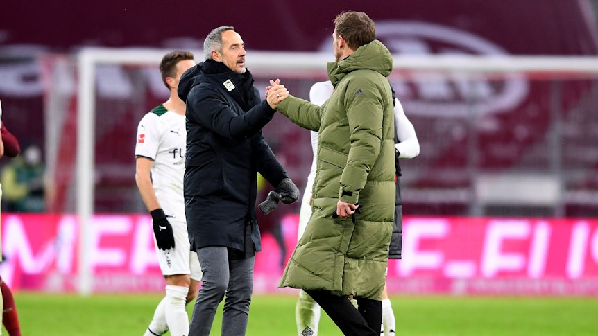 Gladbach-Trainer Adi Hütter (l.) klatscht zum Rückrundenauftakt (7. Januar 2022) in der Allianz-Arena Bayern-München-Coach Julian Nagelsmann (r.) ab. Beide Trainer tragen warme Jacken.