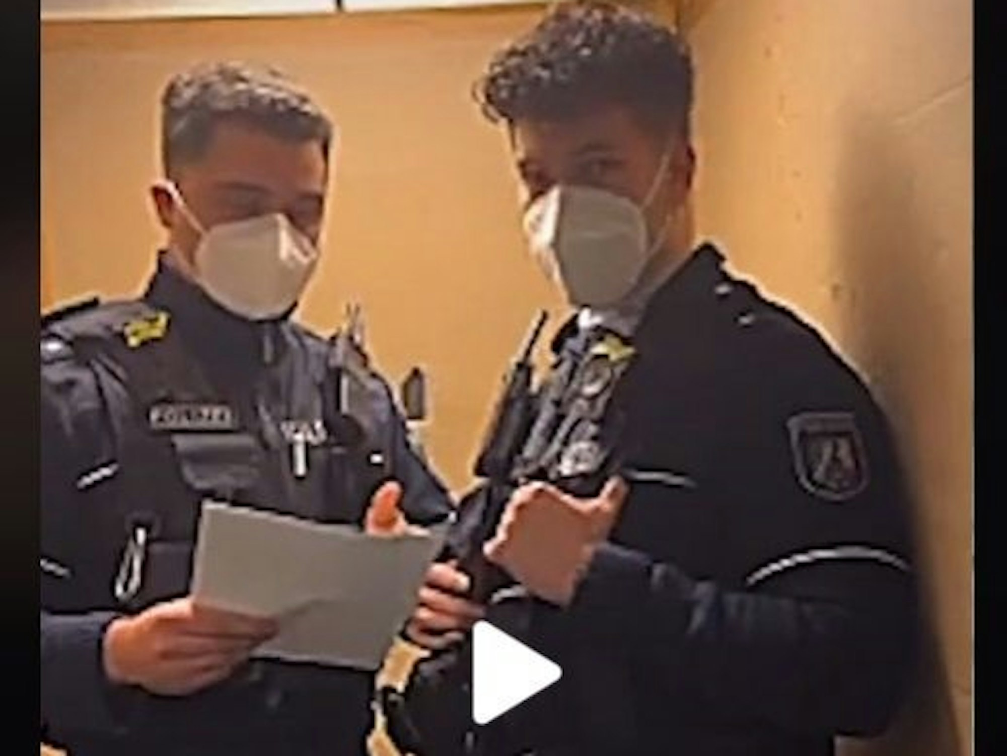 Zwei junge Polizisten stehen in einem Fahrstuhl, der linke hat Unterlagen in der Hand.
