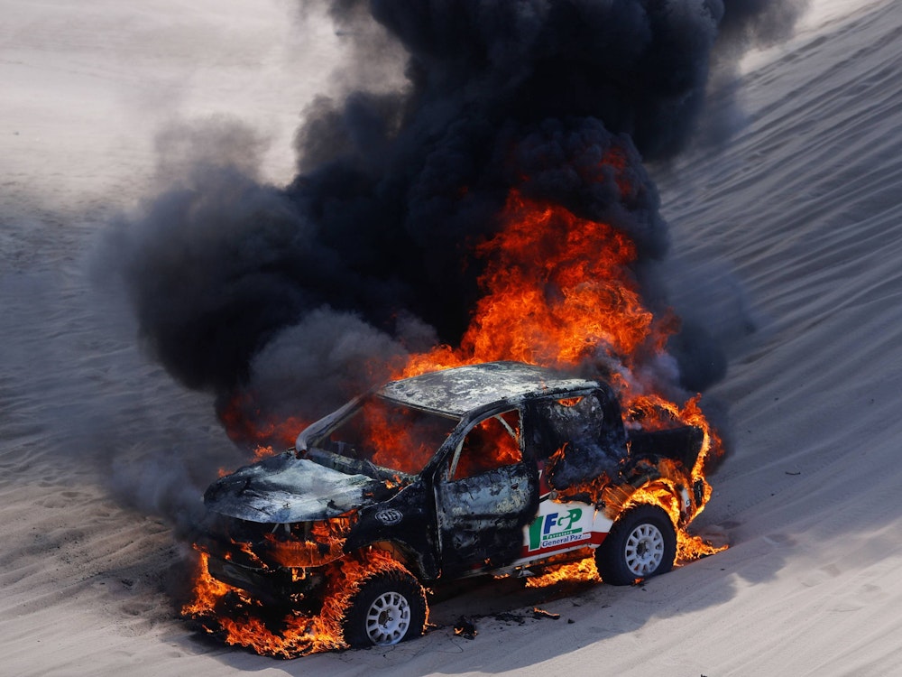Ein Rallye-Wagen steht komplett in Flammen. Schwarzer Rauch steigt auf.