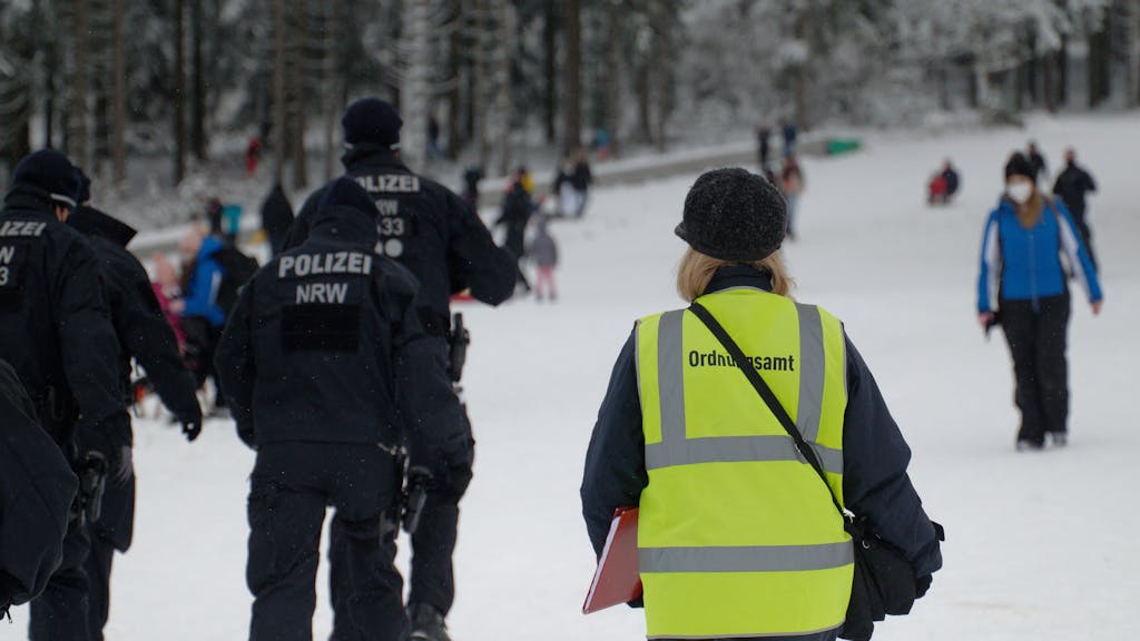 Polizisten und eine Mitarbeiterin des Ordnungsamtes stehen auf einer Piste im Skigebiet in Winterberg.&nbsp;