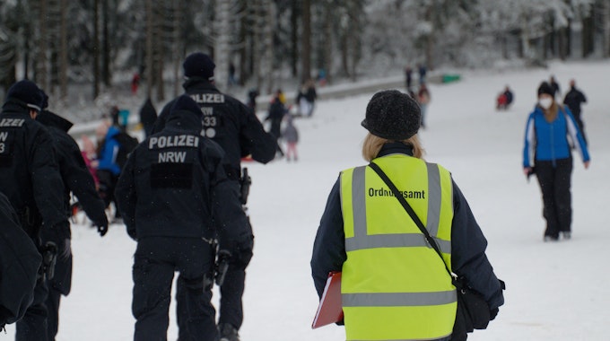 Polizisten und eine Mitarbeiterin des Ordnungsamtes stehen auf einer Piste im Skigebiet in Winterberg.