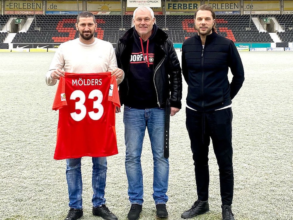 Sascha Mölders präsentiert sein neues Trikot mit der Nummer 33, neben ihm steht Hans-Jürgen Boysen sowie Michael Ferber.