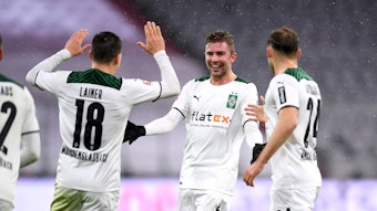 Christoph Kramer (M.) bejubelt mit Stefan Lainer (l.) und Tony Jantschke (r.) den 2:1-Siegtreffer von Borussia Mönchengladbach zum Bundesliga-Rückrundenauftakt (7. Januar 2021) bei Bayern München. Kramer lacht und breitet die Arme aus.