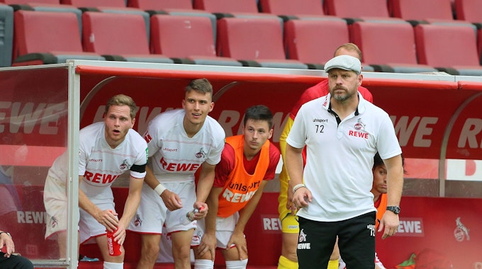 Benno Schmitz, Dejan Ljubicic, Tomas Ostrak und Chefcoach Steffen Baumgart mit überraschten Blicken von der Bank beim Bundesliga-Auftaktsieg des FC gegen Hertha BSC.