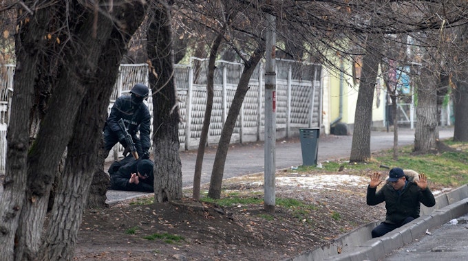 Ein bewaffneter Polizist nimmt am Samstag (8. Januar) zwei Protestanten in Almaty fest. Es seien in Kasachstan mittlerweile fast 6000 Menschen festgenommen worden, darunter viele Ausländer, hieß es. Bei den schweren Unruhen sind offiziellen Angaben zufolge 164 Menschen getötet worden.