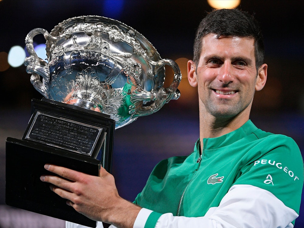 Novak Djokovic hält einen Pokal in den Händen.