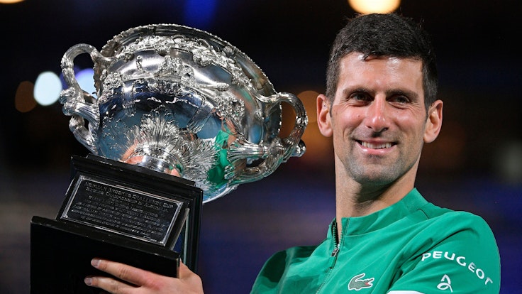 Novak Djokovic hält einen Pokal in den Händen.