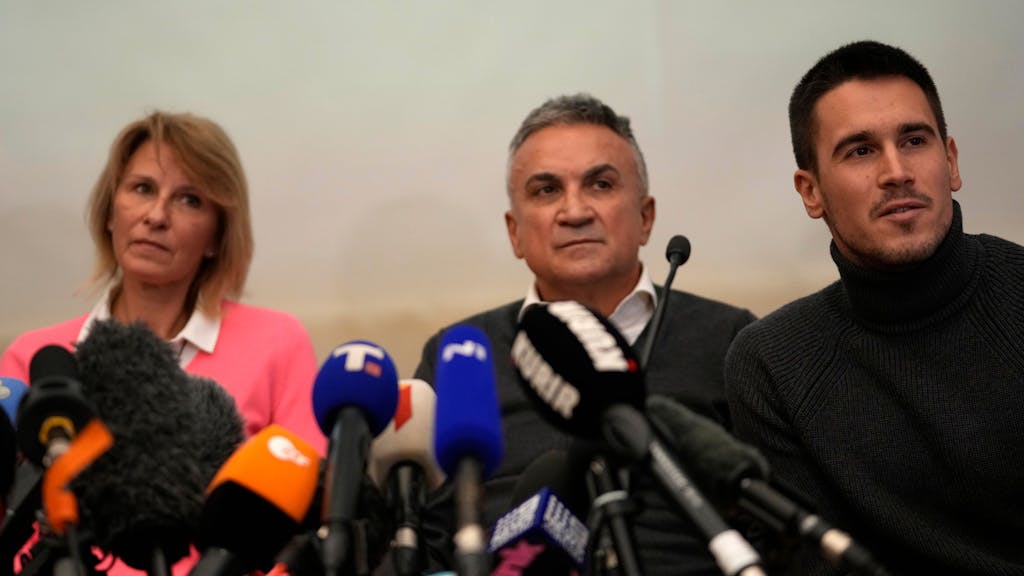 Die Familie von Novak Djokovic sitzt bei einer Pressekonferenz am Rednerpult. 