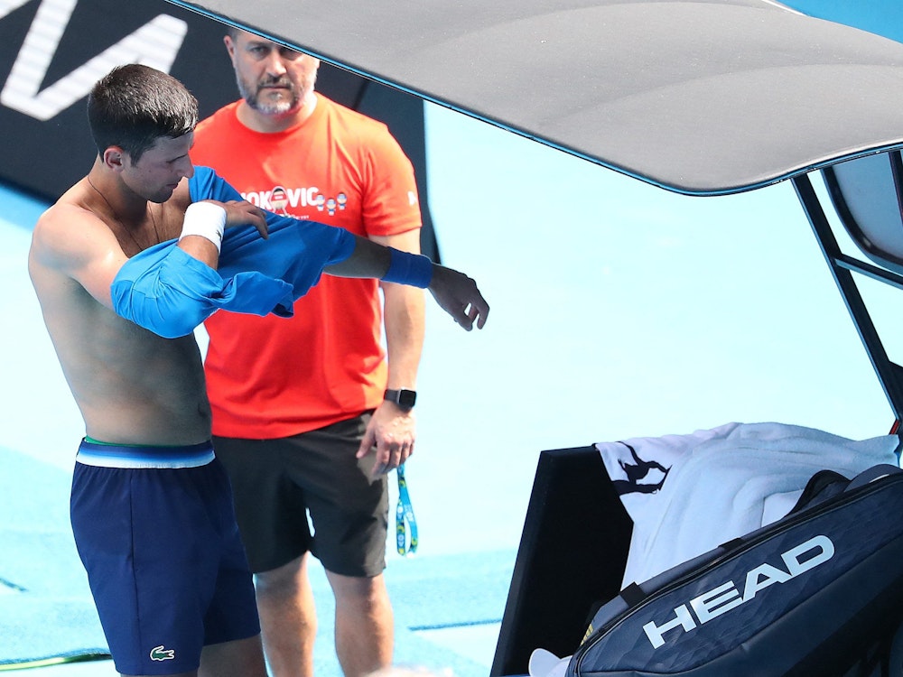 Serbe Novak Djokovic wechselt beim Training ein Shirt.