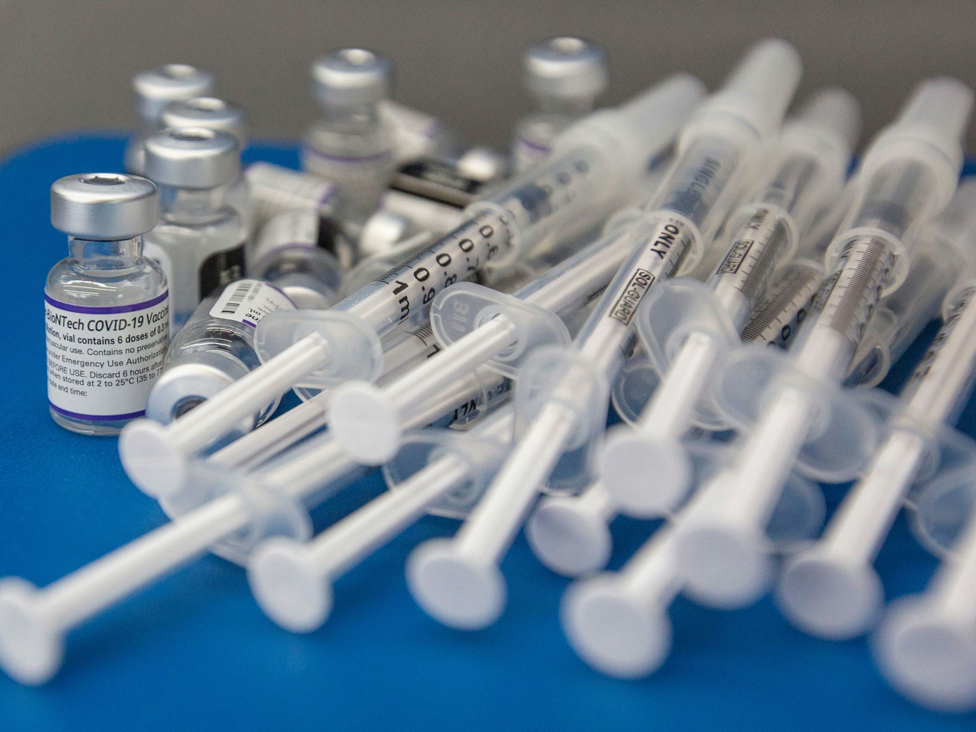 Spritzen und Fläschchen mit dem Impfstoff COVID-19 von Pfizer-BioNTech liegen auf einer Arbeitsfläche.