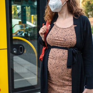 Eine schwangere Frau wartet mit Mund-Nasen-Schutz an einer Haltestelle auf dem Bus. Das Symbolbild wurde am 2. September 2021 aufgenommen.