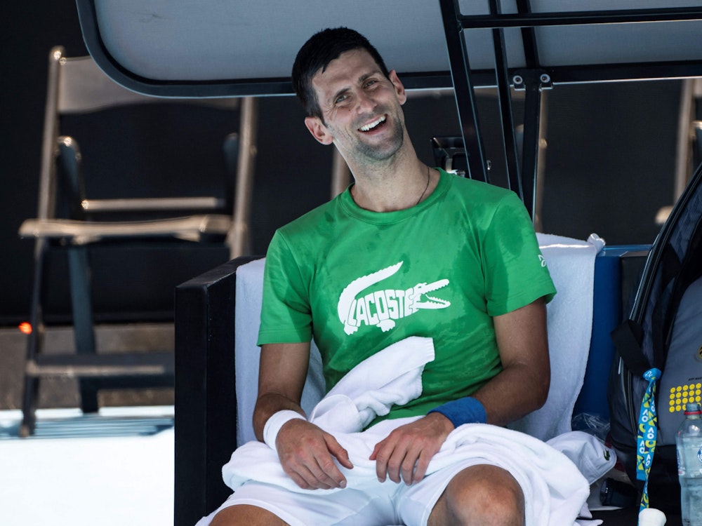 Novak Djokovic lacht während einer Pause im Training in die Kamera.