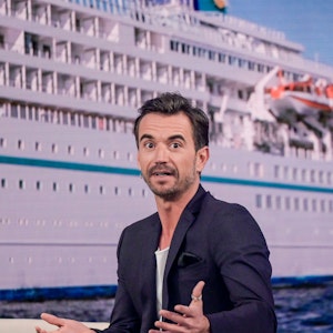 Der Moderator Florian Silbereisen sitzt bei der Aufzeichnung des großen Jahresrückblicks „Menschen 2019“ auf der Bühne. Im Hintergrund ist das ZDF-„Traumschiff“ zu sehen.