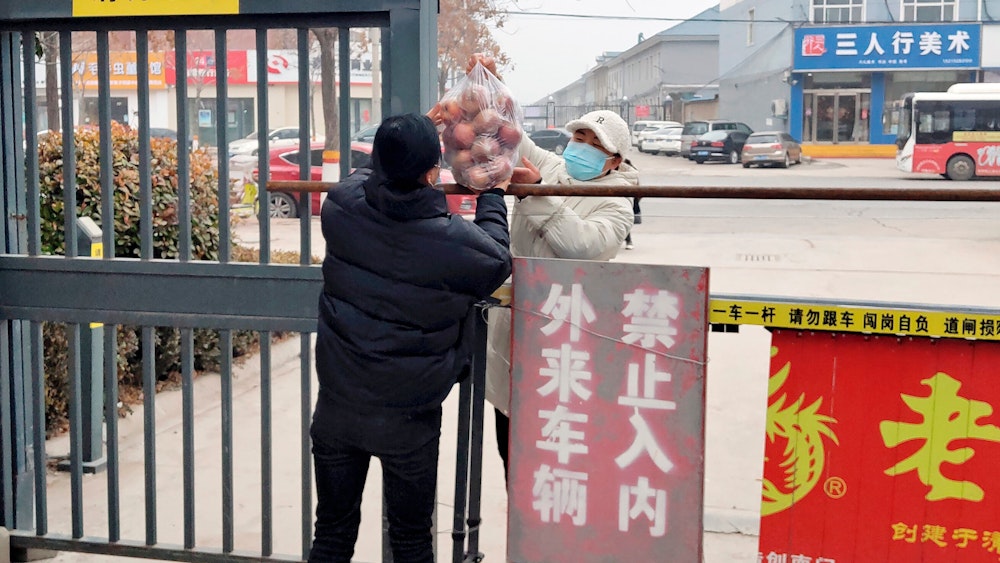 Bewohner reichen Obst über eine Absperrung in einer Gemeinde im Kreis Huaxian in der zentralchinesischen Provinz Henan.
