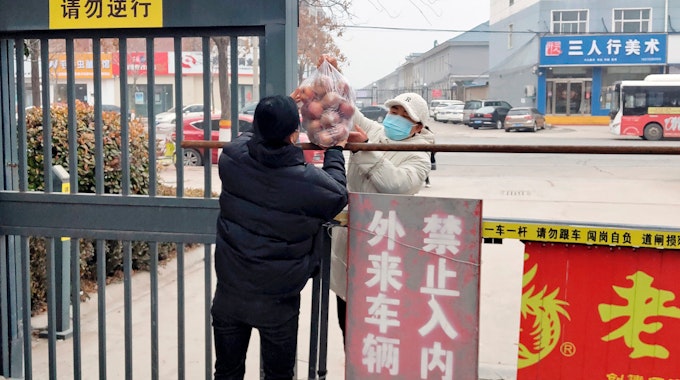 Bewohner reichen Obst über eine Absperrung in einer Gemeinde im Kreis Huaxian in der zentralchinesischen Provinz Henan.