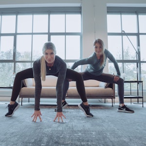 Zwei Frauen beim Barre-Workout in Ballettpositionen.