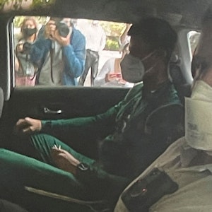 Novak Djokovic (l) sitzt auf dem Rücksitz eines Autos, als er an einem Abschiebehotel ankommt.