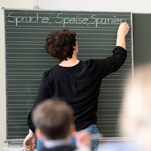 Eine Lehrerin schreibt in einer Grundschule Worte an eine Tafel.