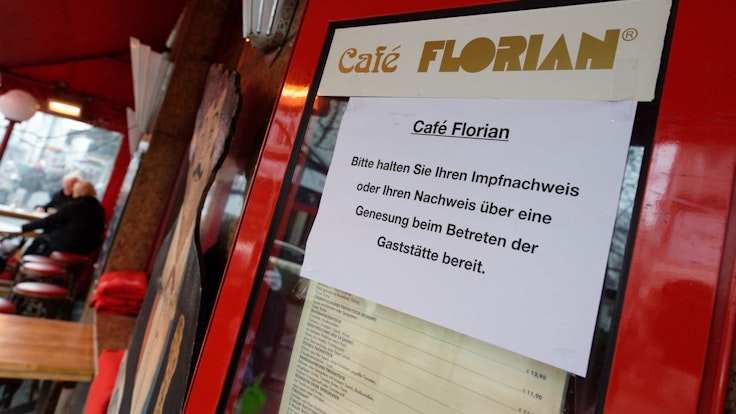 12.01.2022, Nordrhein-Westfalen, Düsseldorf: Ein Schild am Eingang zum Café Florian fordert die Gäste zum bereithalten des Impfnachweises auf.