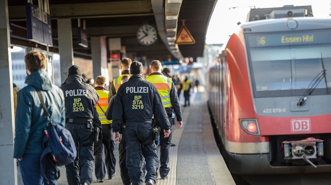 Einsatzkräfte der Bundespolizei laufen am Bahnhof Köln Messe/Deutz auf einem Bahnsteig, an dem eine Bahn hält, entlang.