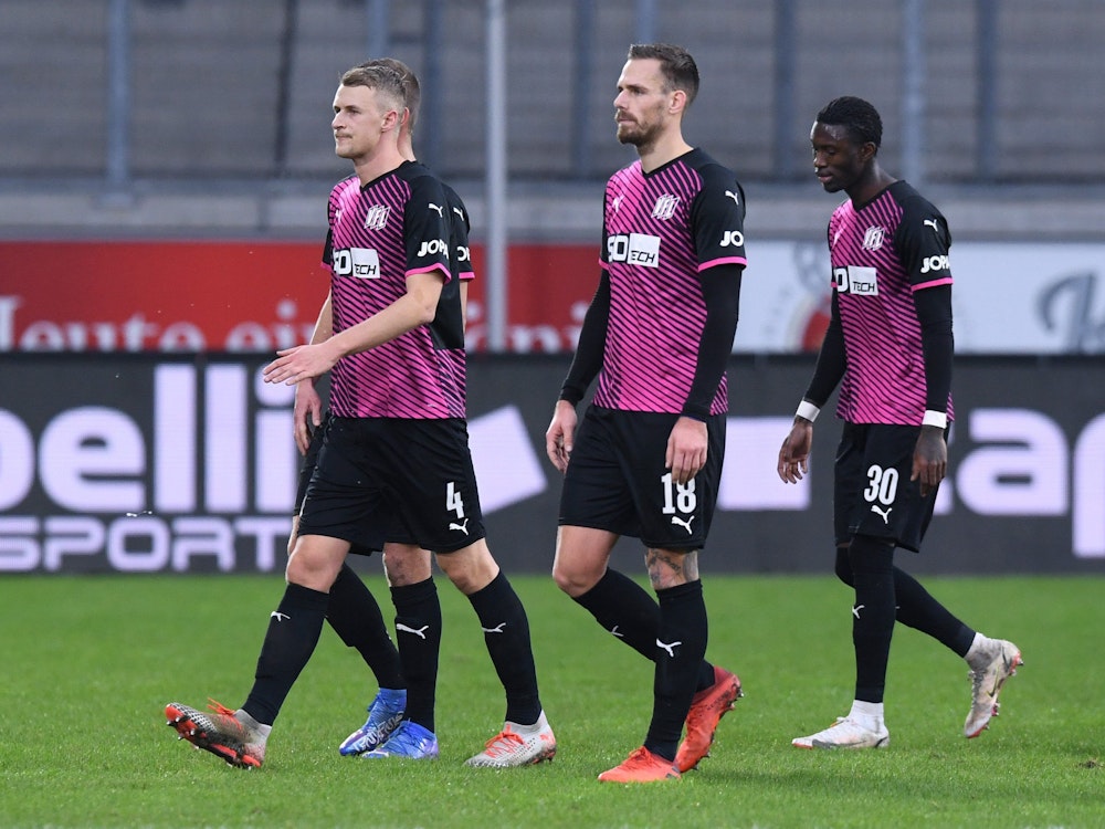 Osnabrücks Aaron Opoku (r) verlässt nach rassistischen Beleidigungen von den Zuschauerrängen mit Teamkollegen das Stadion.