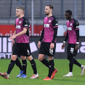 Osnabrücks Aaron Opoku (r) verlässt nach rassistischen Beleidigungen von den Zuschauerrängen mit Teamkollegen das Stadion.