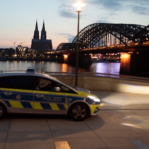 Ein Polizeiauto fährt am Rheinufer Streife. Foto von der dpa