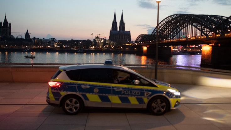 Ein Polizeiauto fährt am Rheinufer Streife. Foto von der dpa